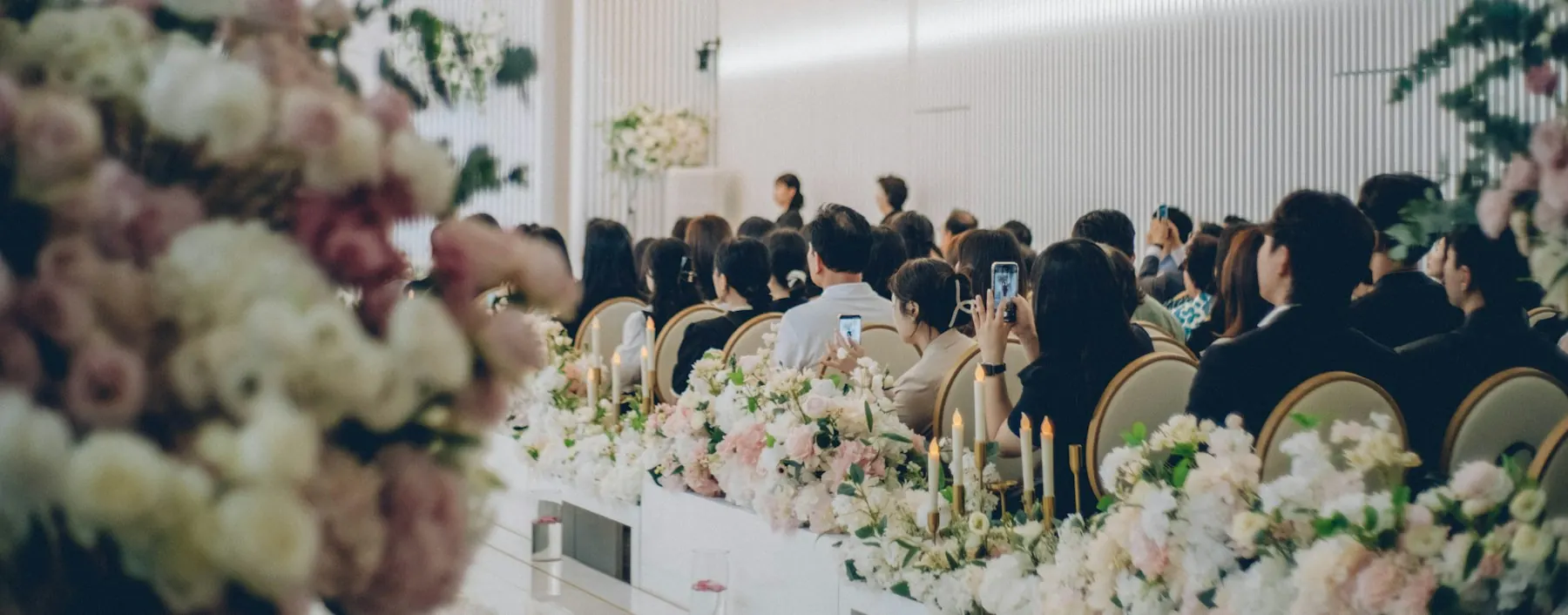 Guests seated for a formal event surrounded by flowers and candles