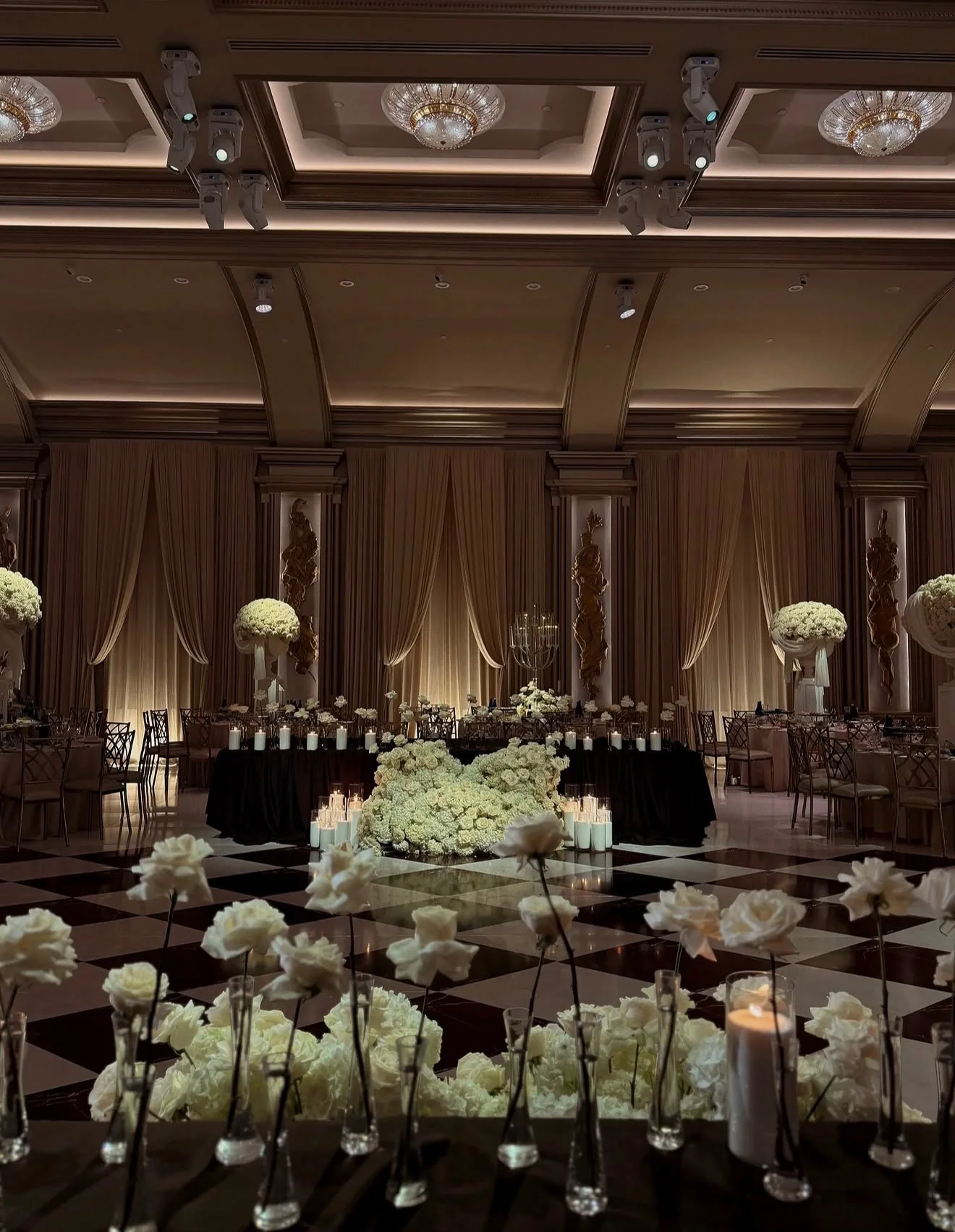 A ballroom transformed with white flowers, candlelight, and draped walls